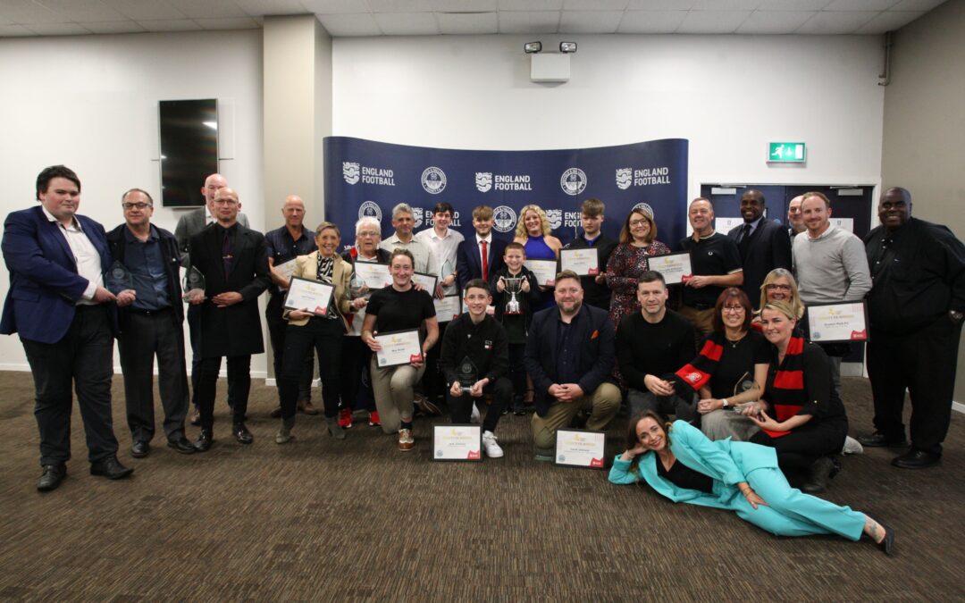 The winners and highly commended nominees for the Sheffield FA's Grassroots Football Awards in 2023 smile in front of a banner, holding their certificates.