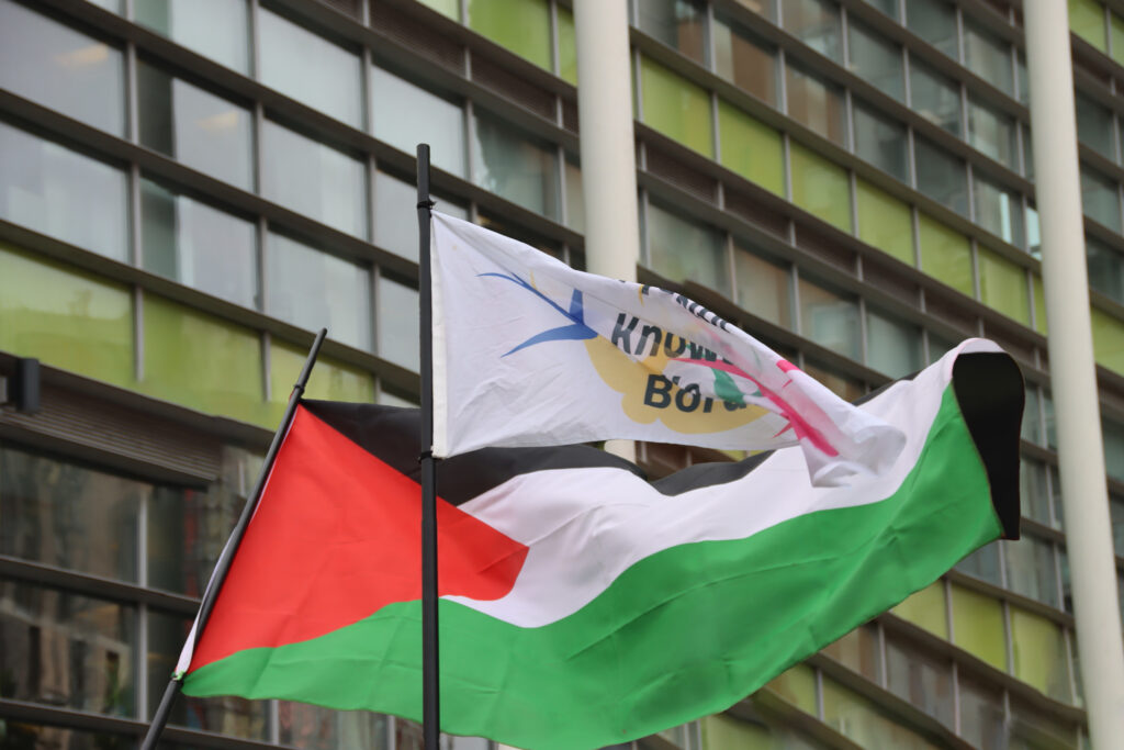 A Palestine flag behind a white flag, in front of the Home Office building in Sheffield.