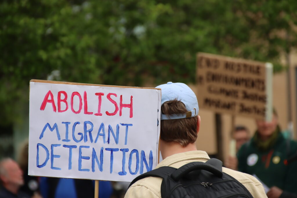 A sign reading 'ABOLISH MIGRANT DETENTION'