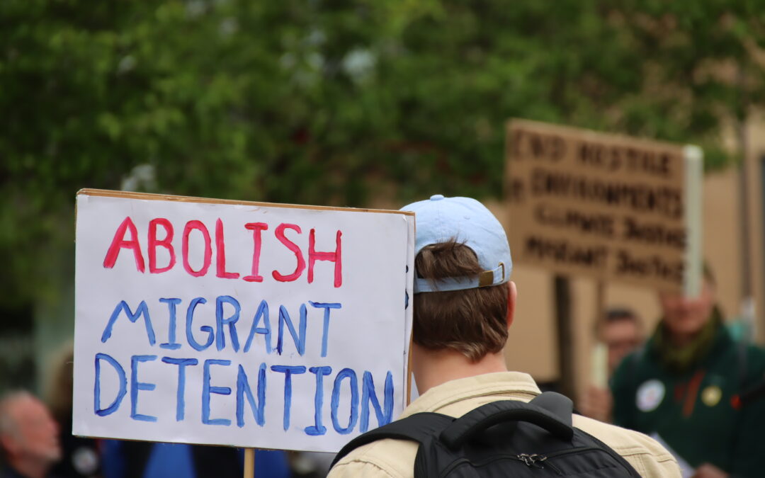 A sign reading 'ABOLISH MIGRANT DETENTION'