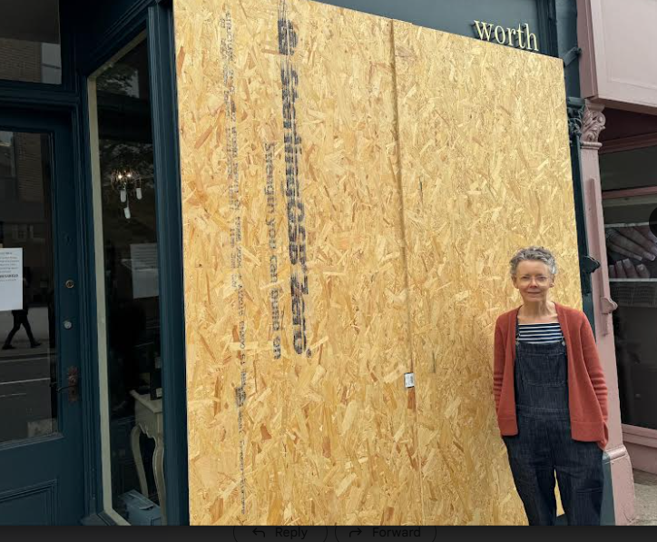 Sarah Worth stood outside her shop, Worth interiors with boarded up windows.