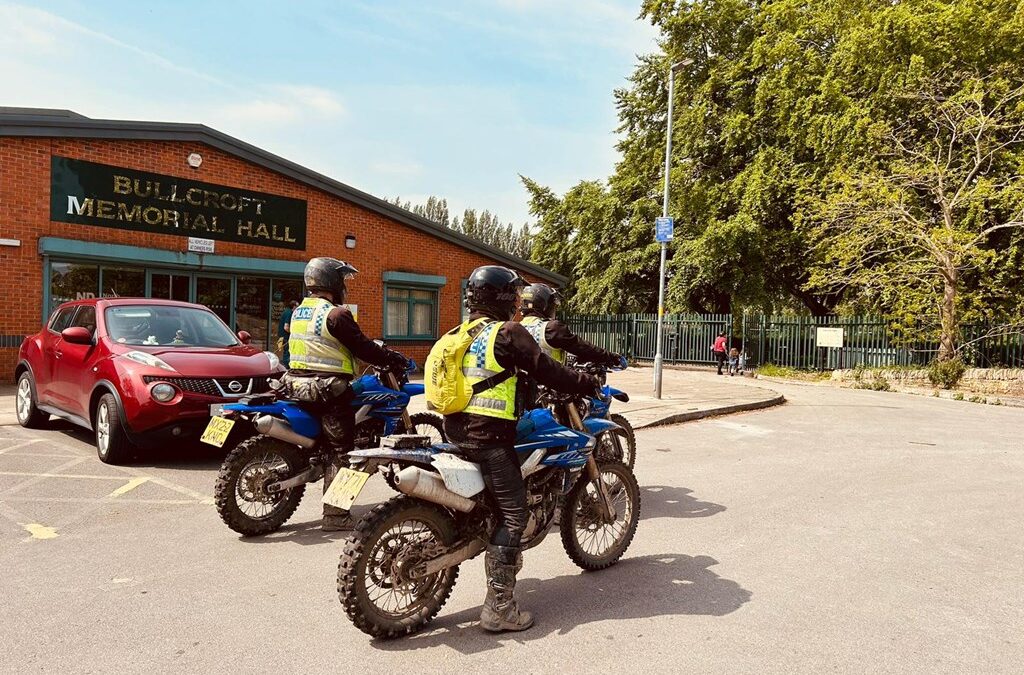 Police officers on bikes in high-vis uniforms in a car park.