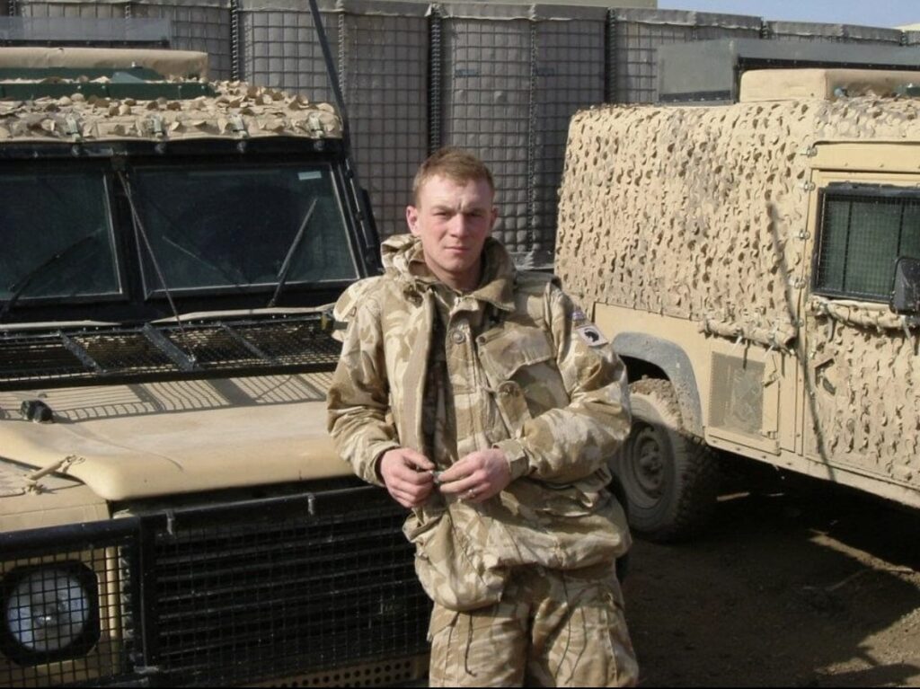 Gary Devonport stood by two camouflaged vehicles in camouflage uniform