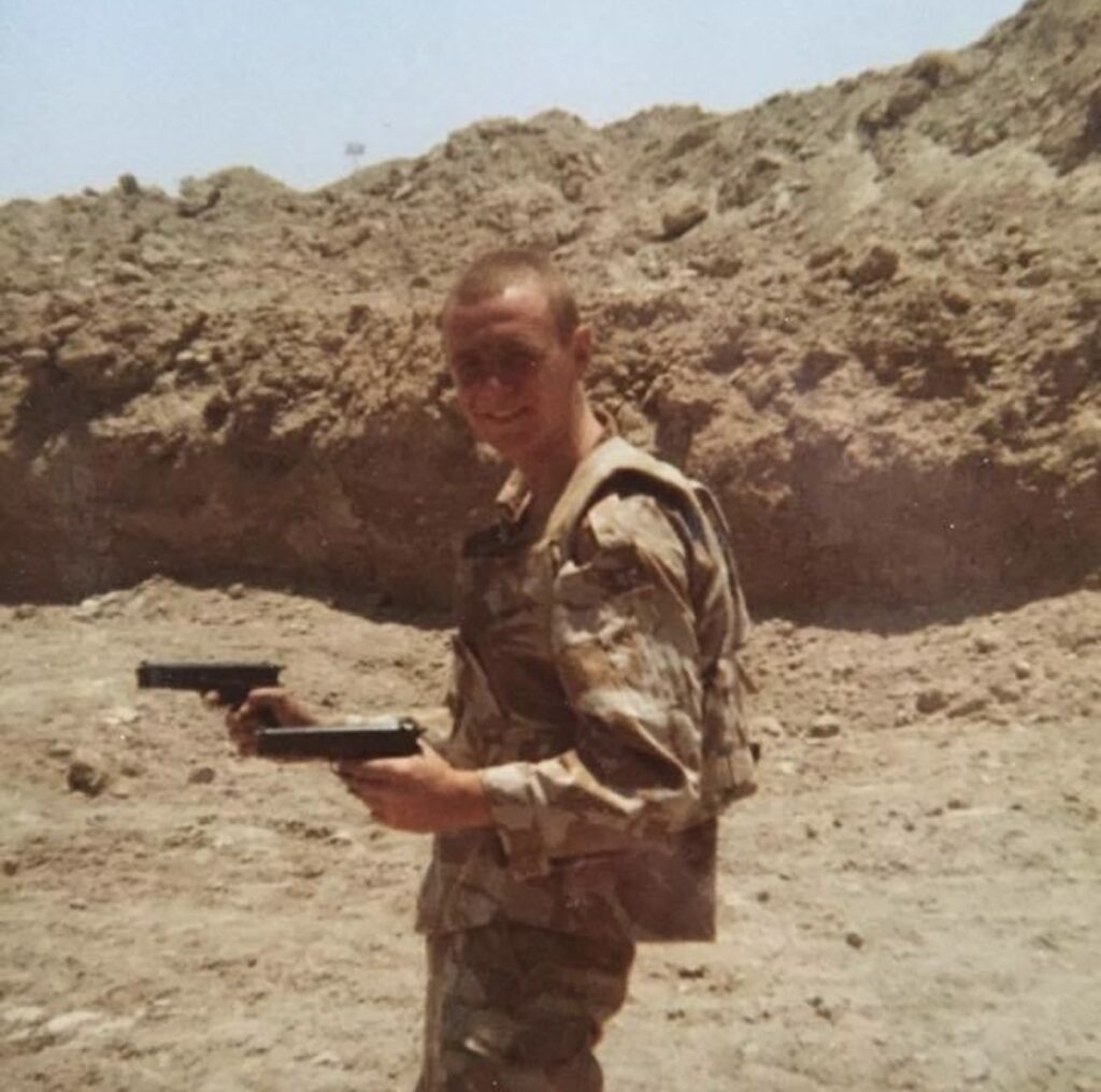 Gary Devonport serving in the army, wearing camouflage uniform and holding two pistols