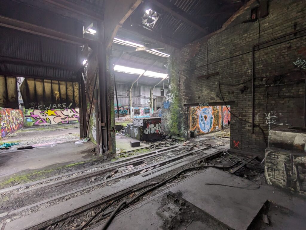 Inside a large disused factory with rubble on the floor