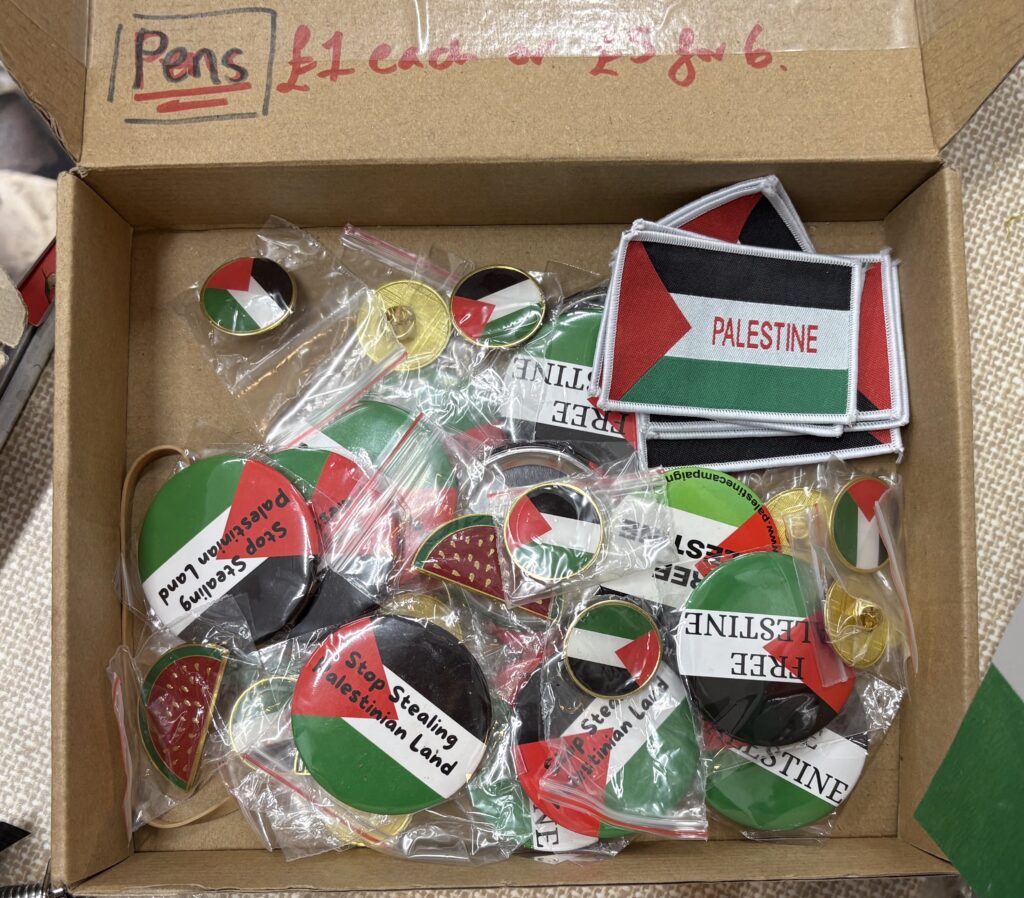 A carboard box filled with Palestine-themed stickers and pins. 