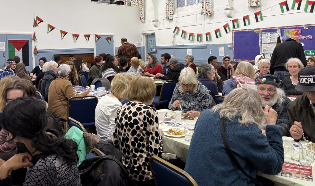 A large group of people seated at tables, eating and talking.