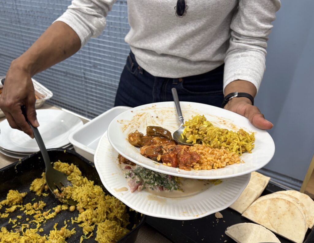 A woman filling two plates with food from a buffet.
