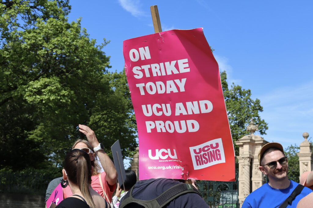 Pink Sign over someone's back saying On strike today. UCU and proud 