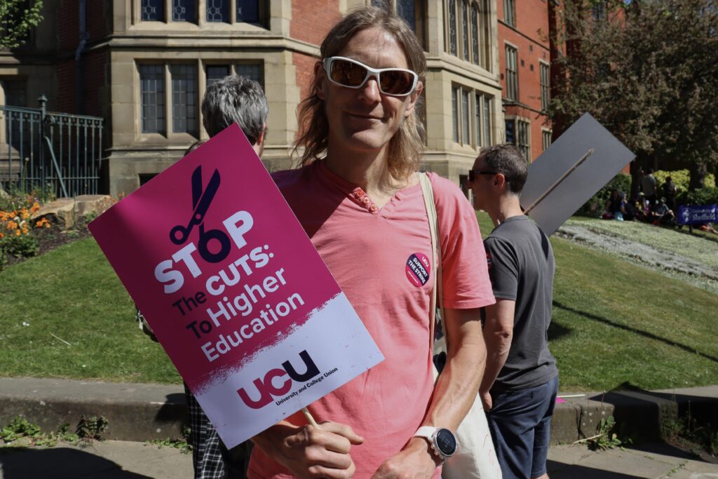 Oli Johnson at the strike holding a Stop the Cuts to higher education sign