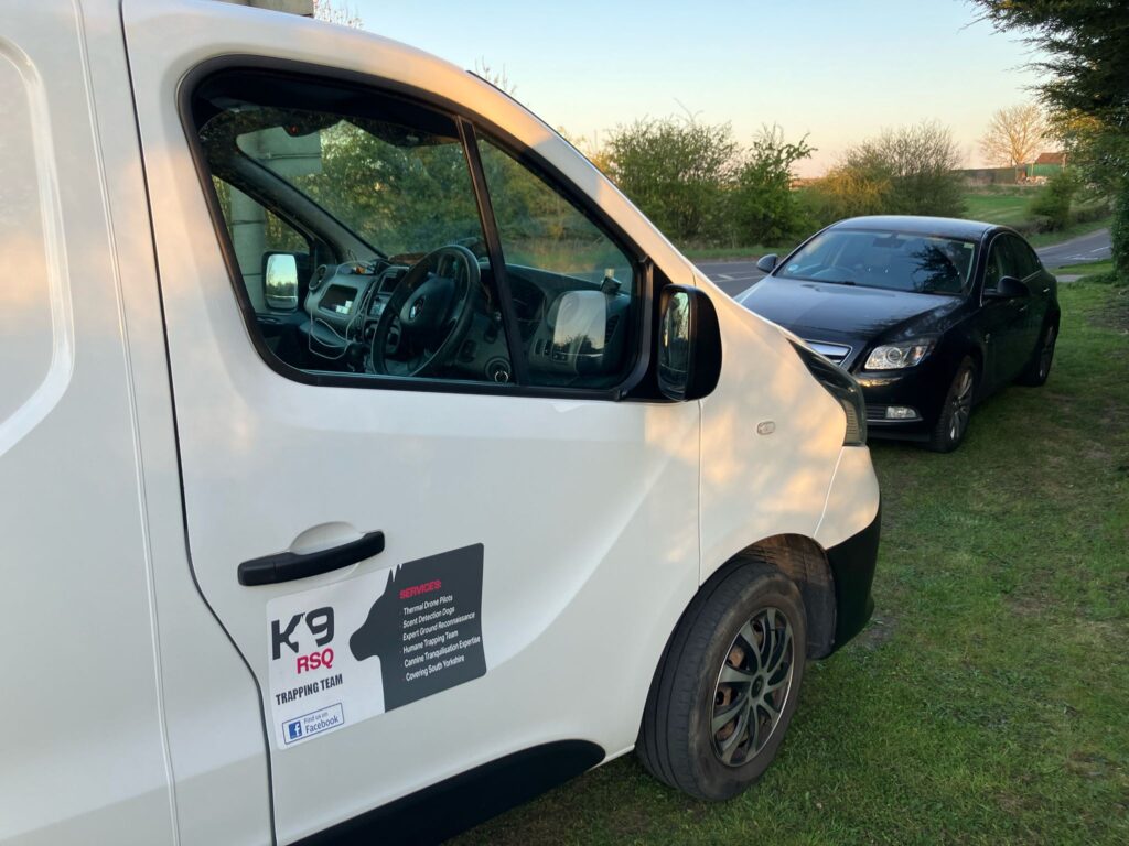 A white van with the logo 'K9-RSQ' on the bottom of the van door in grey and pink colours.