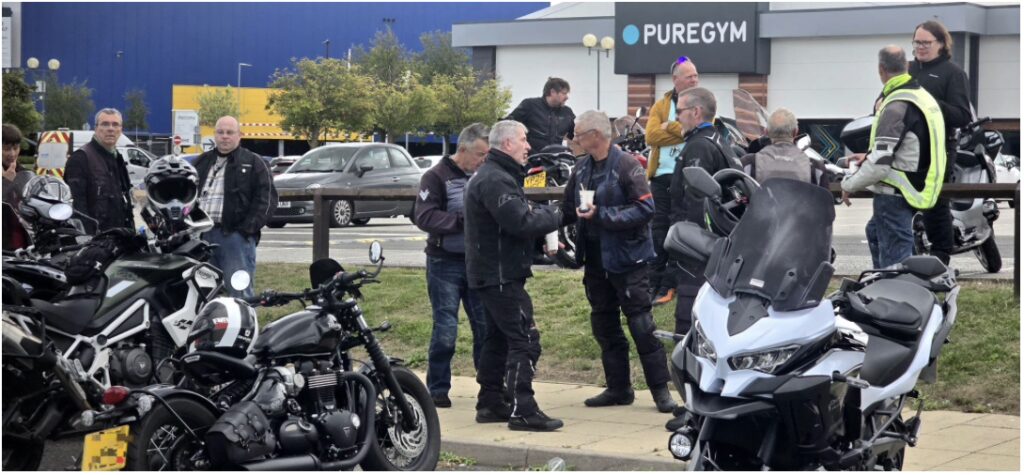 Men having a chat in front of their motorbikes. Puregym is in the background