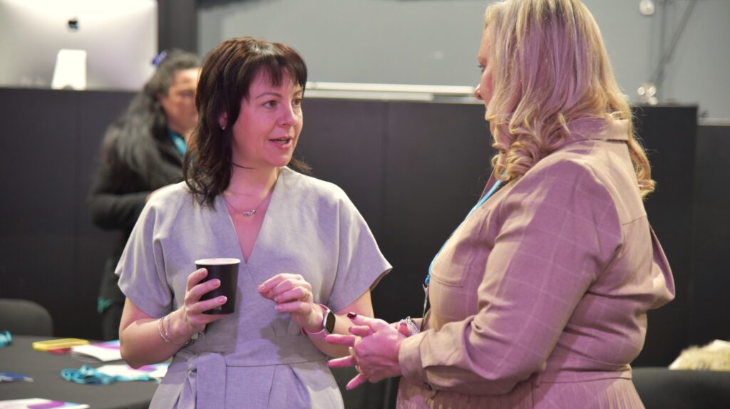 two women having a conversation about the conference over a cup of coffee