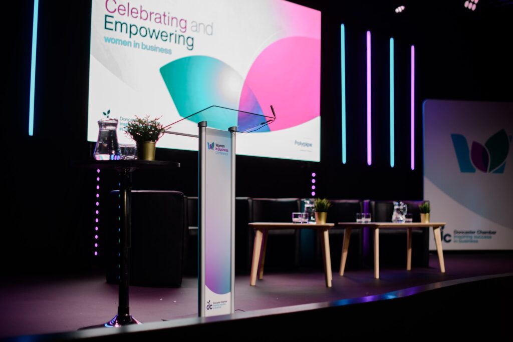 a stage with a PowerPoint slide behind stating 'celebrating and empowering'