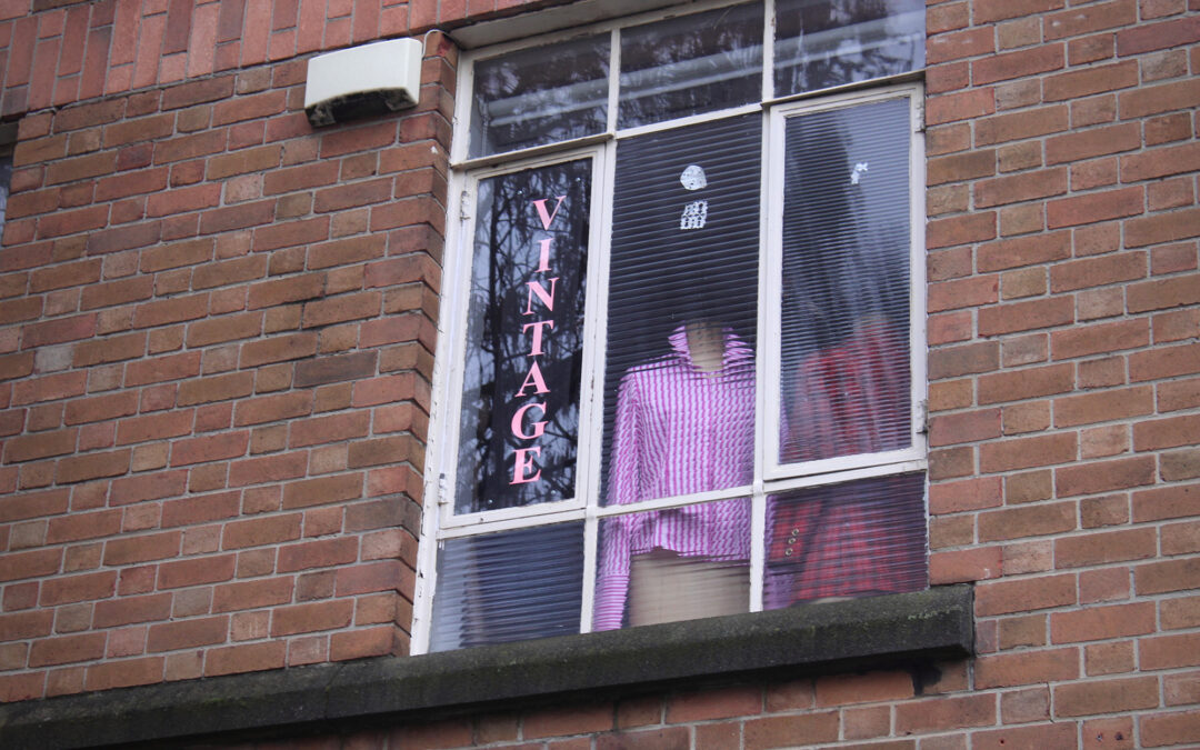 A window displaying vintage clothes with a sign saying 'vintage' in pink text.