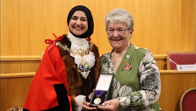 Lady receiving an award from the Lord Mayor and holdiing award