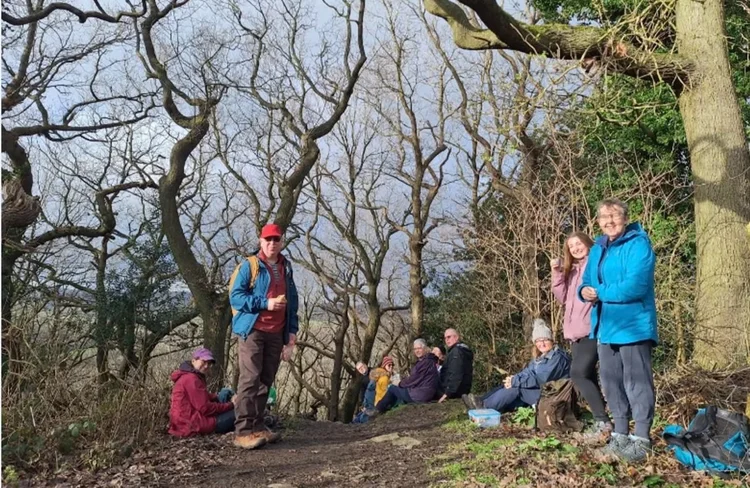 Group of white men and women on a woodland trail in outdoor clothing.