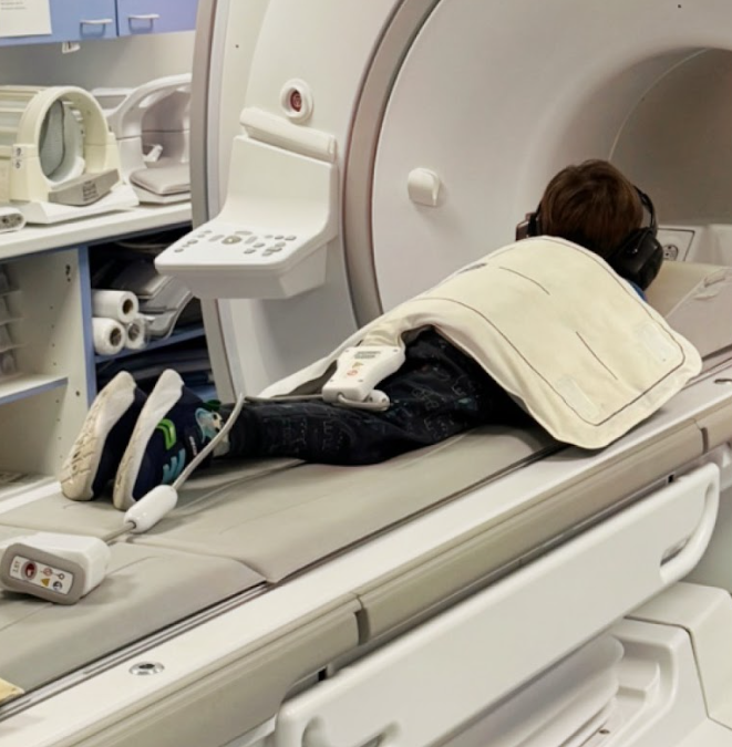 A young boy wearing headphones going in for an MRI scan