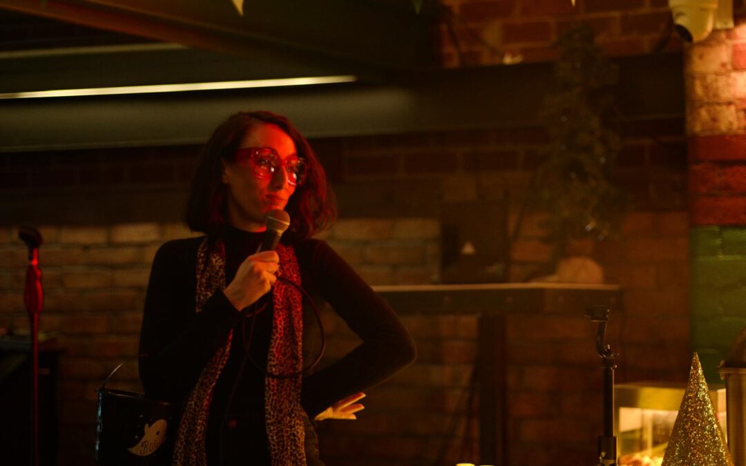 April Thompson holds a microphone on stage.