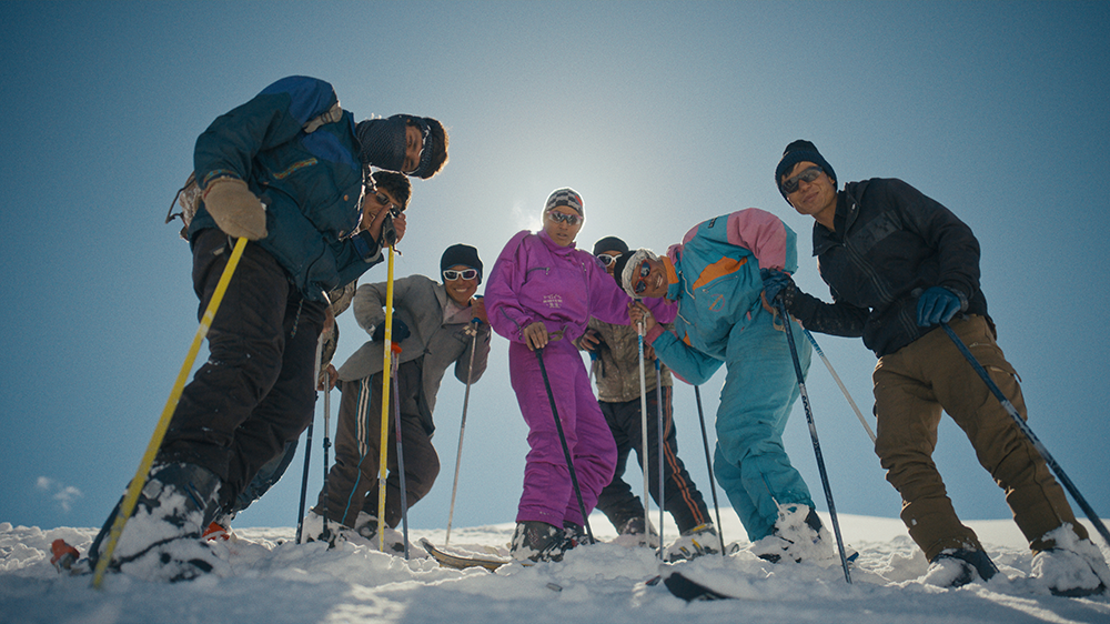 skiers stood together looking down at camera in the snow