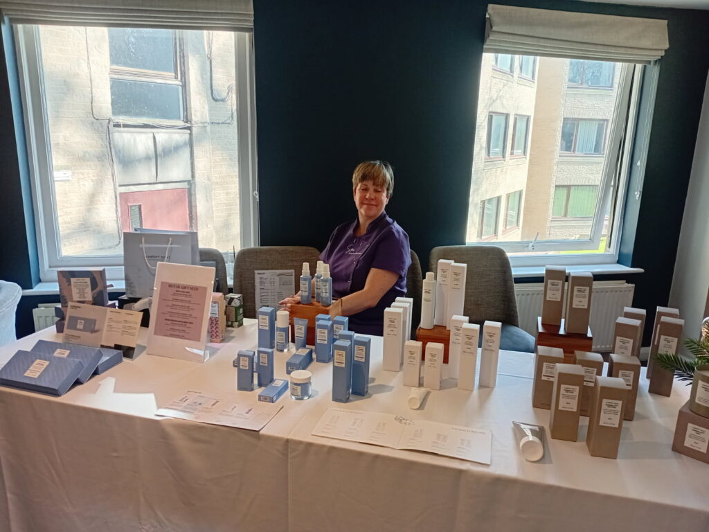 A member of staff at the spa standing in front of a table with various wellness products.