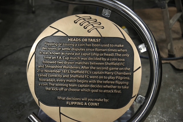 A photo of football statue close up and showing engraved text.