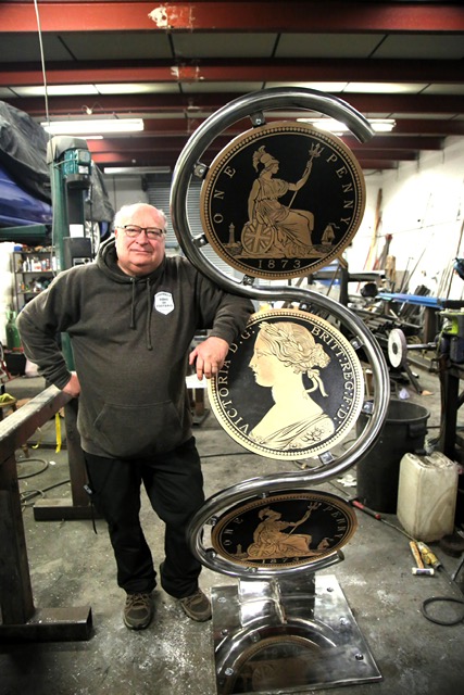 A photo of Sheffield Home of Football secretary John Clarke leaning against statue of spinning coins.