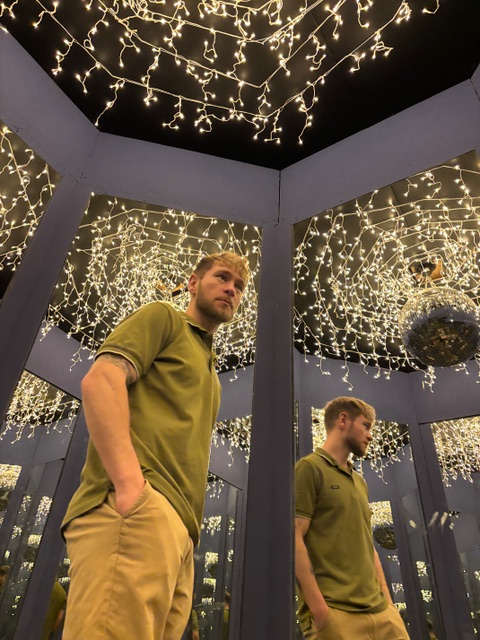 Man in a mirror room with fairy light 