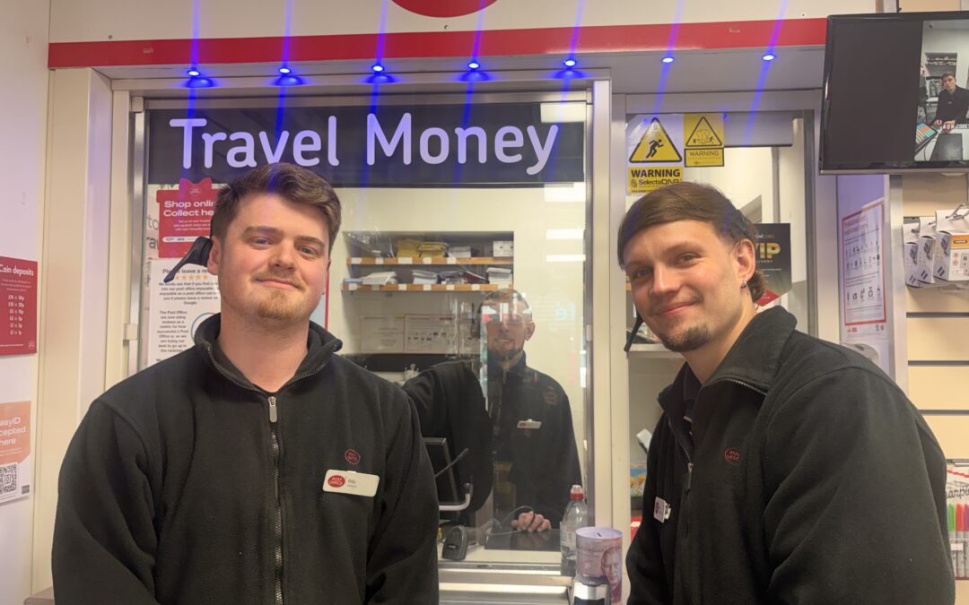 Two Post Office workers smiling in front of their parcel collecting stand