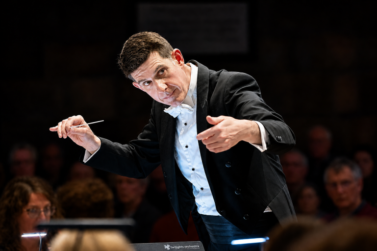 Conductor Quentin Clare leaning, forward while conducting 