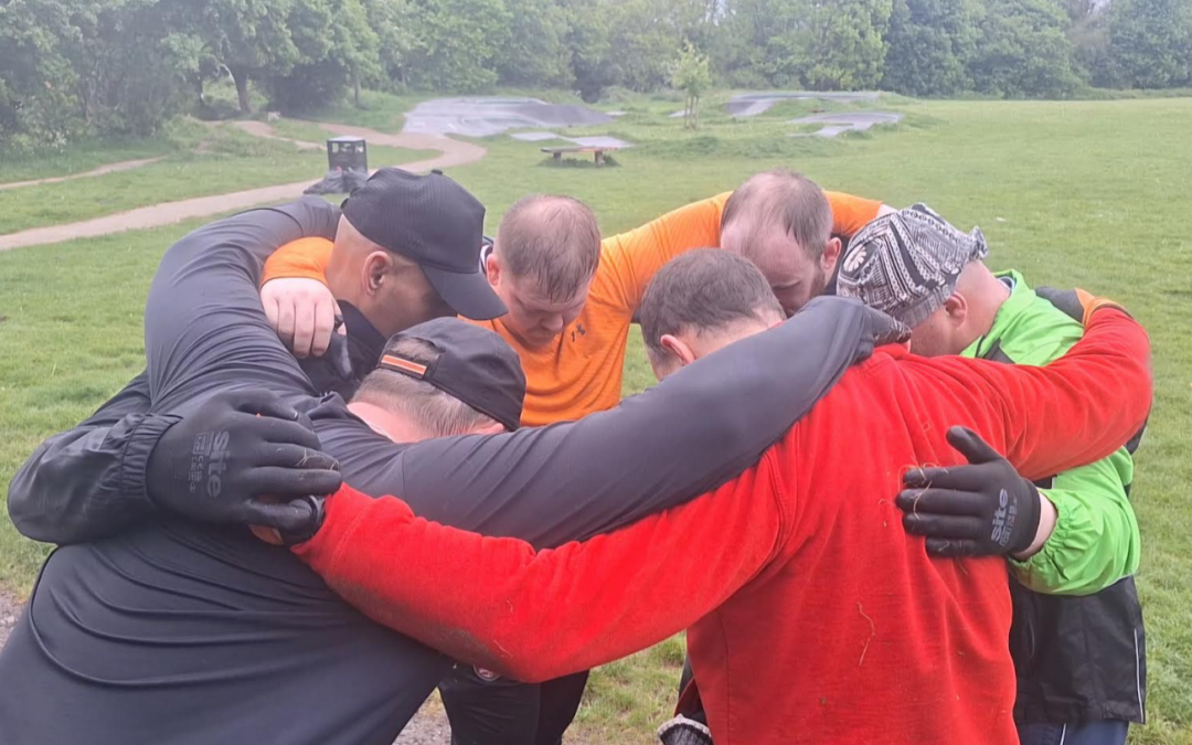 An image of a group of men huddled around, embracing eachother.