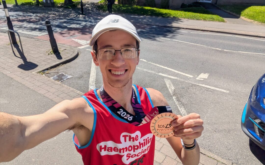 A man in running clothes holding a medal from The London Marathon
