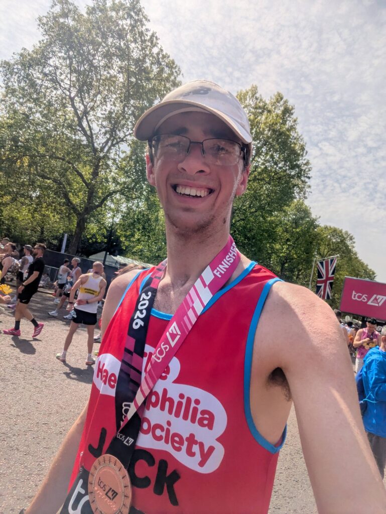 A man looking very tired after finishing The London Marathon with a medal around his neck
