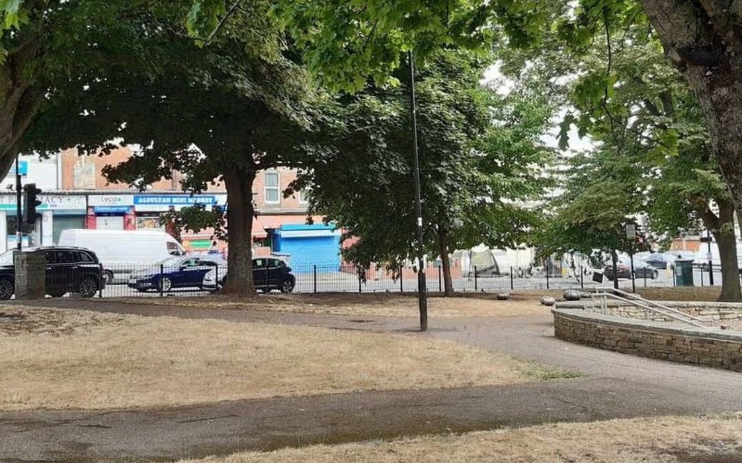 Ellesmere Green, in the foreground is an empty park, in the background trees and businesses.